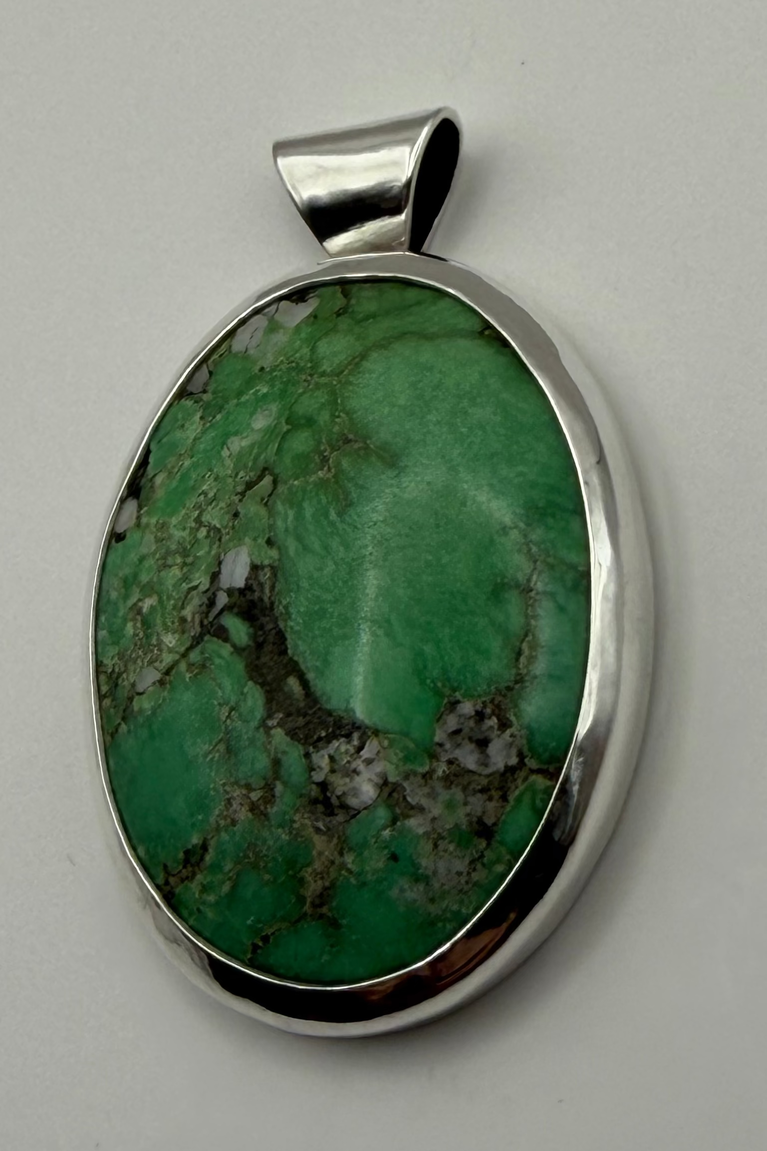 Green stone set in sterling silver. Displayed on white backdrop
