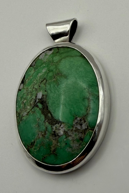 Green stone set in sterling silver. Displayed on white backdrop