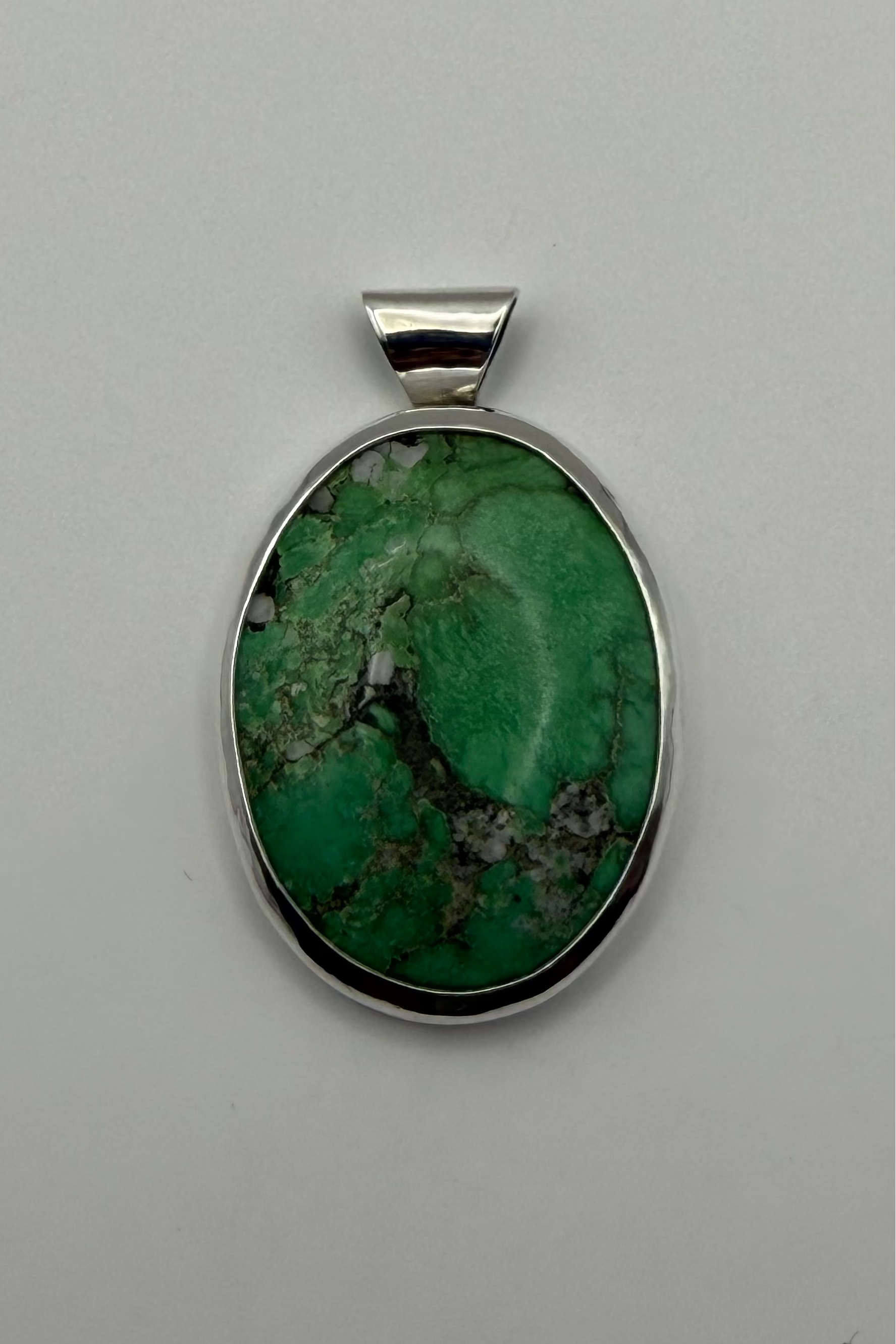 Green stone set in sterling silver. Displayed on white backdrop.
